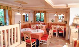 A cozy restaurant with wooden interior and red fabric. Cozy tables and chairs await the guests.