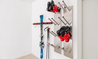 A ski room with hanging skis and ski boots. The wall is designed in a minimalist and functional style.