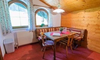 A cozy dining area with a wooden table and comfortable benches. Large windows let in plenty of light and create an inviting atmosphere.