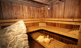 A cozy sauna with a wooden bench and natural stone wall. The ambiance is warm and inviting.