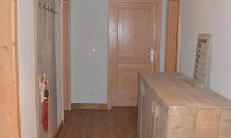 A spacious hallway with wooden doors and a rustic sideboard. The walls are painted light and the ceiling lamp provides pleasant lighting.