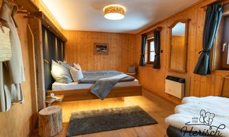 A cozy bedroom with wood paneling, a large bed, and warm colors. Large windows and stylish decor create an inviting atmosphere.