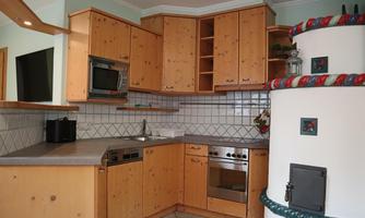 A modern kitchen with wood-colored cabinets and an elegant countertop. The appliances include a stove, a sink, and a built-in oven.