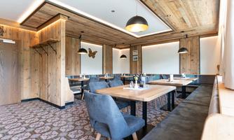 A cozy restaurant with wooden walls and modern furniture. The tables are stylishly set, and the lighting creates a pleasant atmosphere.