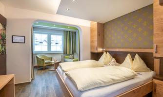 A modern bedroom with two beds and wooden decor. The room is bright and cheerful, with a cozy seating area.
