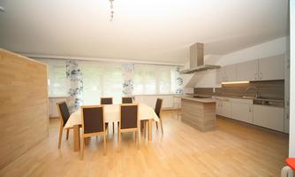 A modern dining room with a large table and chairs. The bright kitchen is well-equipped and offers plenty of space.