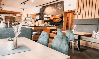 A modern café with wooden decor and cozy seating. The reception area is bright and inviting, with a board for daily specials.