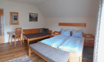 A cozy room with two beds and a sitting area. The room is bright and simply furnished.