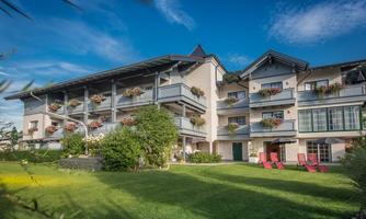 A beautiful building with balconies and blooming plants. The adjacent garden is green and inviting.