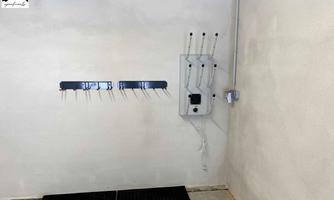 An empty room with a bright wall.  
On the wall, there are several mounts and a panel with electrical connections.