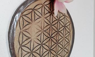 A round wall hanging with a geometric pattern and a delicate flower. The combination of natural materials and craftsmanship adds a warm atmosphere to the room.