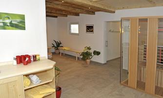 A bright and inviting wellness area with a wooden ceiling and plants. On the left side, drinks and towels are ready.