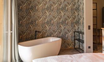 A modern bathroom with a freestanding bathtub and a decorative wall. The space is bright and stylishly designed.