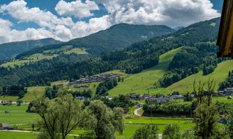 A picturesque mountain landscape with gentle hills and lush greenery. The sky is clear with a few white clouds.