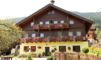 A beautiful wooden house with colorful flower balconies. The surroundings are green and picturesque.