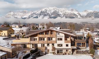 A modern building in a snowy landscape with mountains in the background. The sky is clear and the place looks inviting.