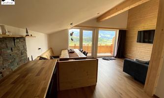 A modern apartment with wood decor and large windows that offer a beautiful view. The area is bright and inviting with an open kitchen and a cozy living area.