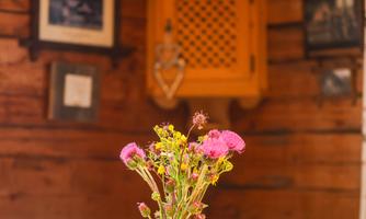 A beautiful table with a flower vase in the center. In the background, rustic wooden walls and decorations are visible.