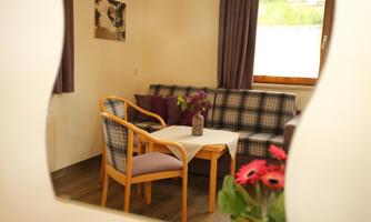 A cozy living space with a sofa and a table. On the table, there is a vase with flowers.