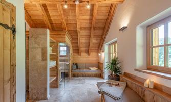 A stylish room with wooden ceilings and light walls. Cozy seating and plants create a relaxed atmosphere.