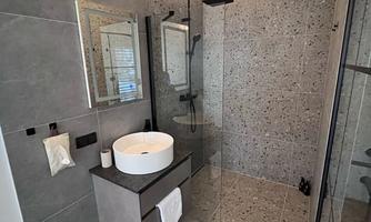 A modern bathroom with a walk-in shower and a stylish sink. The walls are painted in a neutral gray tone, creating an elegant atmosphere.