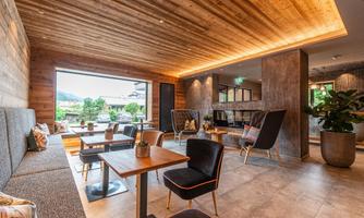 A modern lounge with wood paneling and elegant furniture. Large windows provide a view of the outdoors and let in plenty of light.