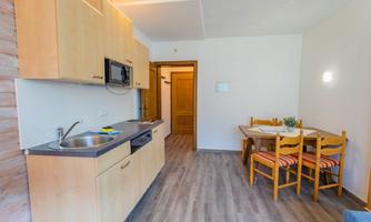Modern kitchen with wooden cabinets and a dining table. Bright rooms with stylish flooring.