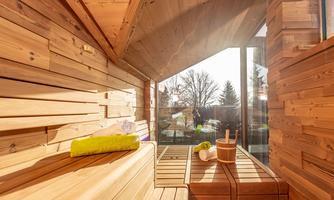 A modern sauna with wooden walls and large windows. The interior design is simple and inviting, perfect for relaxation.