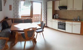 A cozy kitchen with a dining area and wood paneling. Bright colors and a window provide plenty of natural light.