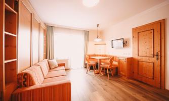 A cozy living space with wooden shelves, a sofa, and a dining table. The large window lets in plenty of light and creates an inviting atmosphere.