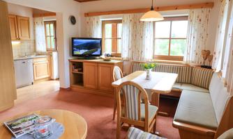 A cozy apartment with wooden details and large windows. The living area is furnished with a table and a seating area.