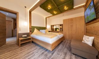 A modern bedroom with wood decor and a large bed. The room design is bright and inviting, with a cozy seating area.