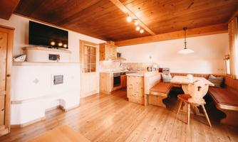 A cozy kitchen with wooden details and a bench. The room is bright and inviting, perfect for social gatherings.