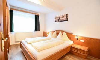 A cozy bedroom with a double bed and wooden interior. The room has plenty of daylight and a calm atmosphere.