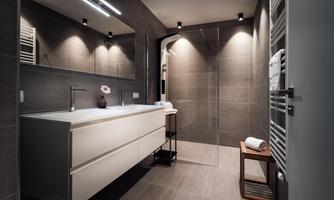 A modern bathroom with an elegant shower and a stylish sink. The walls are in gray shades and the lighting is pleasant.