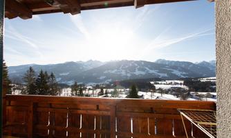 A beautiful view from a balcony of snow-covered mountains. The sun is shining brightly over the landscape.