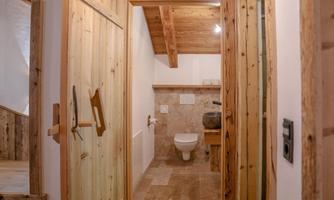 A modern bathroom with wooden doors and a rustic flair. The walls are in neutral tones, and a sink is clearly visible.