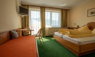 A comfortable hotel room with two beds and an additional sleeping space.  
Large windows ensure plenty of daylight and a beautiful view.