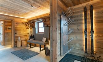 A modern entrance area made of wood with skis and a bench. The room is designed to be bright and welcoming.