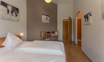 A cozy bedroom with two single beds and wooden flooring. Pictures of winter sports hang on the walls.