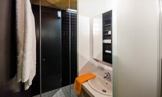 A modern bathroom with a shower and a sink. Towels are hanging on the wall and there is a bright, friendly atmosphere.