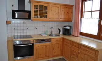 A cozy wooden kitchen with modern appliances. The windows let in plenty of daylight and create an inviting atmosphere.