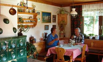 A cozy dining room with a table and two people drinking coffee together. The walls are decorated with pictures, and the room has a warm, inviting atmosphere.