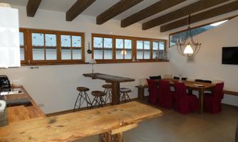A modern kitchen with wooden shelves and rustic furniture. The room is bright and inviting, with windows that let in plenty of light.