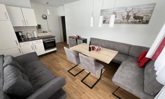 A modern kitchen with a dining area and a comfortable sofa. The room is bright and invitingly designed.