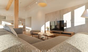 A modern living room with a cozy couch and a television. Large windows let in plenty of light and create an inviting atmosphere.