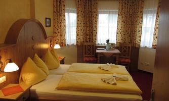 A cozy bedroom with two single beds and yellow pillows. Large windows provide plenty of daylight and a welcoming atmosphere.