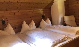 A cozy room with wooden paneling and several beds. The atmosphere is warm and inviting, perfect for relaxation.
