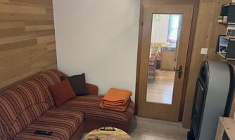 A cozy living space with a striped sofa and a small table. The wooden walls give the room a warm atmosphere.
