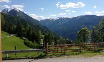 A breathtaking mountain landscape with green meadows and snow-capped peaks. The sky is clear and blue, creating a peaceful atmosphere.